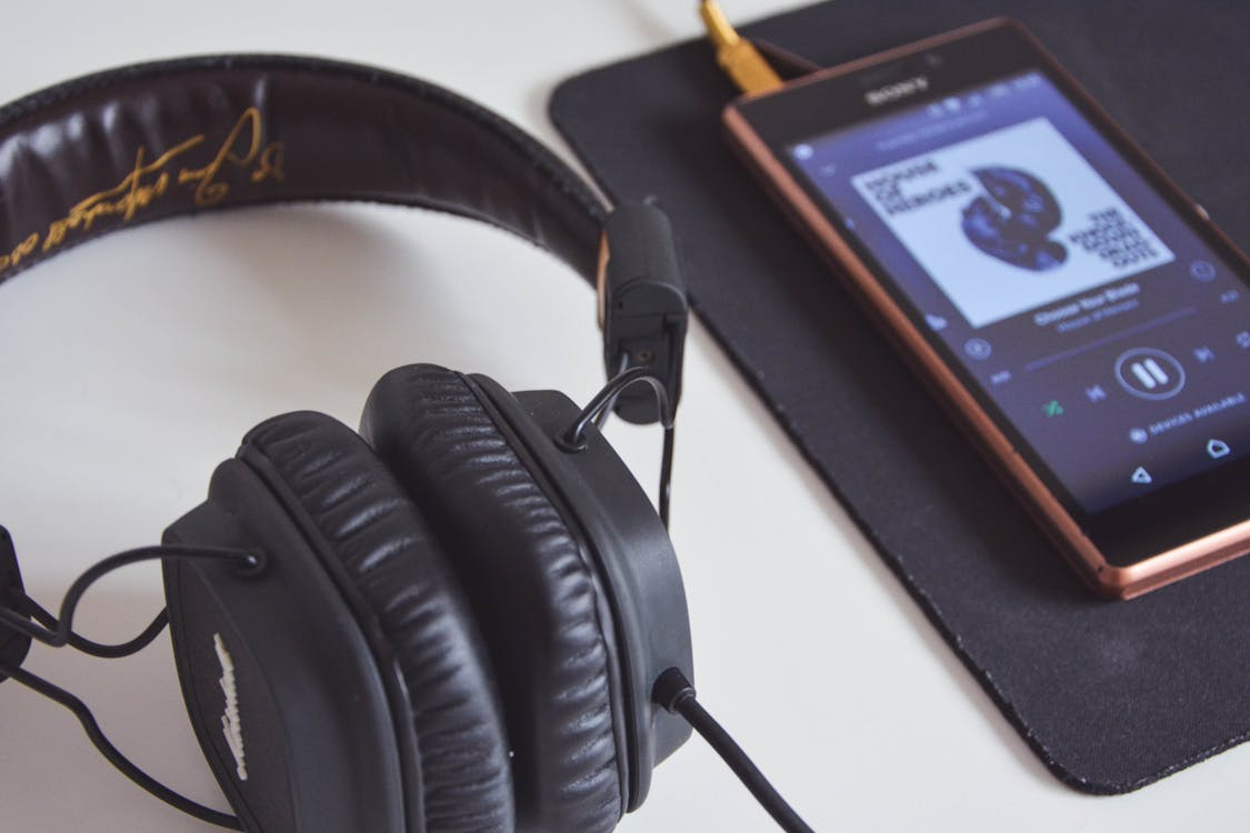 Streaming music discovery shown through headphones and a music app playing on a phone.