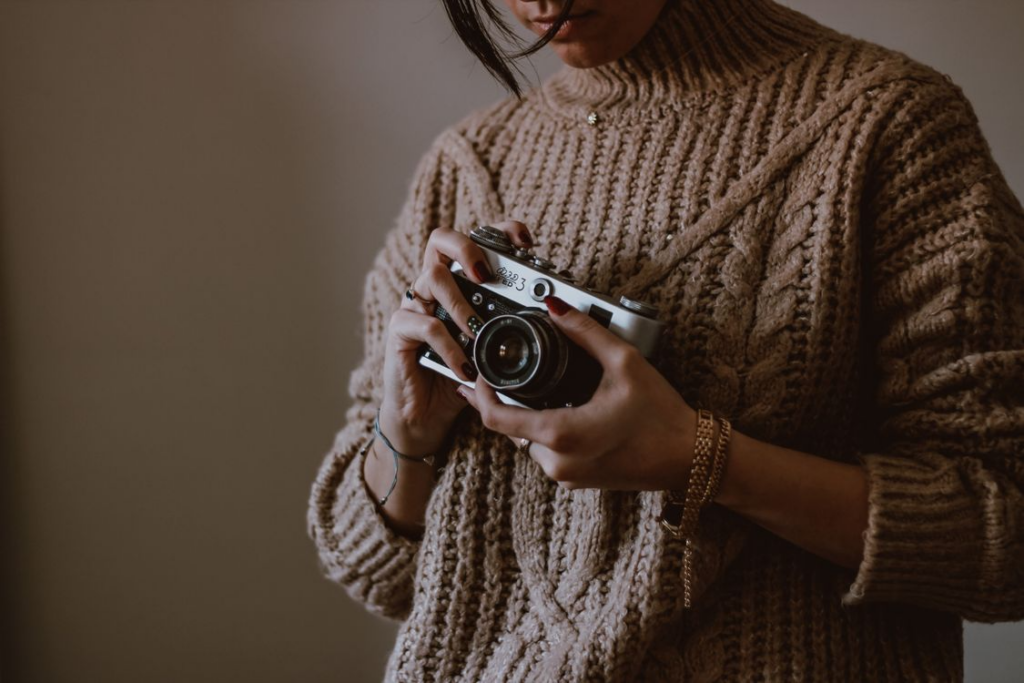 Woman holding a film camera for analog hobbies for digital fatigue.