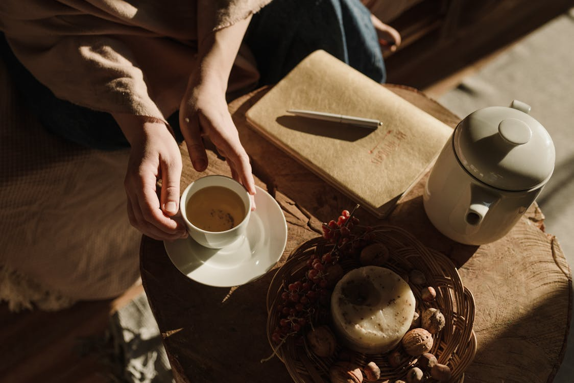 Tiny luxuries in everyday life shown through tea, a journal, and a cozy table setup.