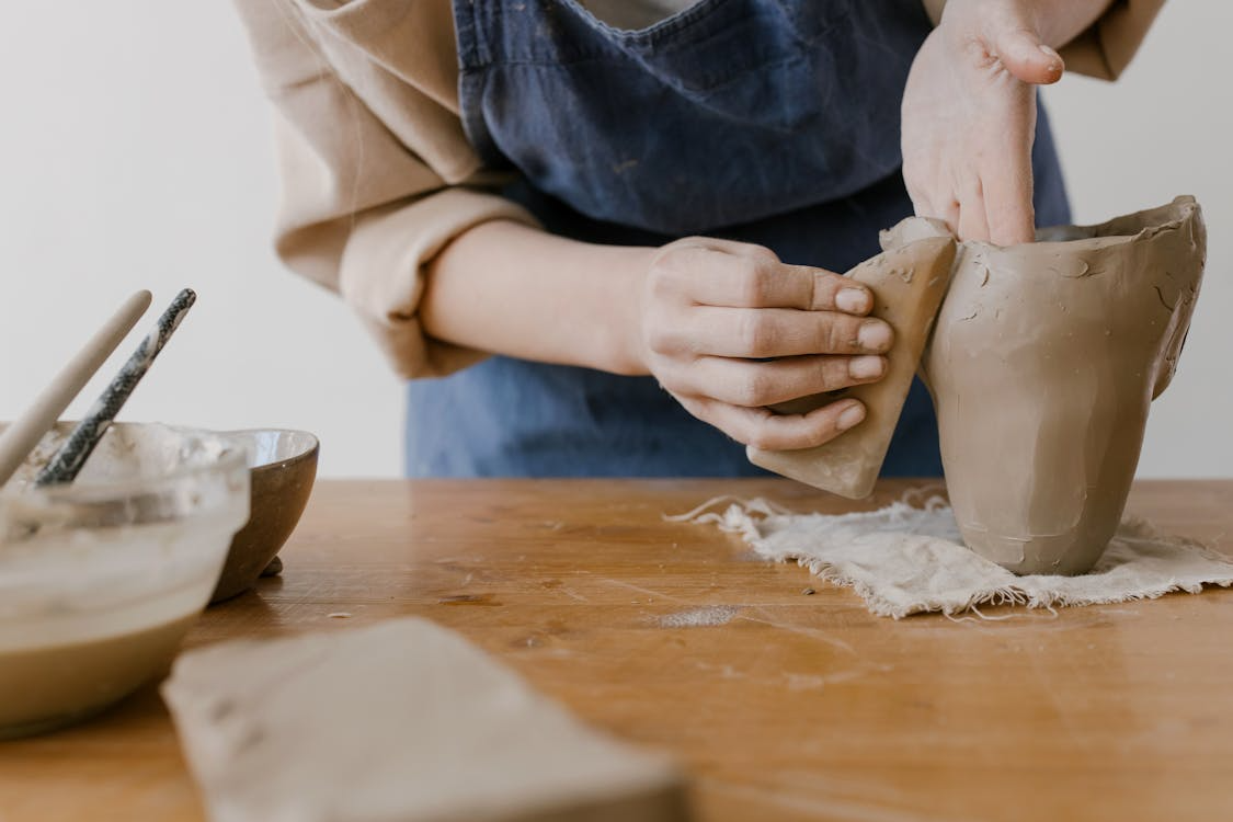 Learning creative skills as an adult shown through hands shaping clay during pottery practice.