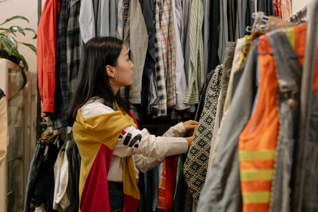 Secondhand shopping trend shown through a shopper browsing clothes on a thrift store rack.