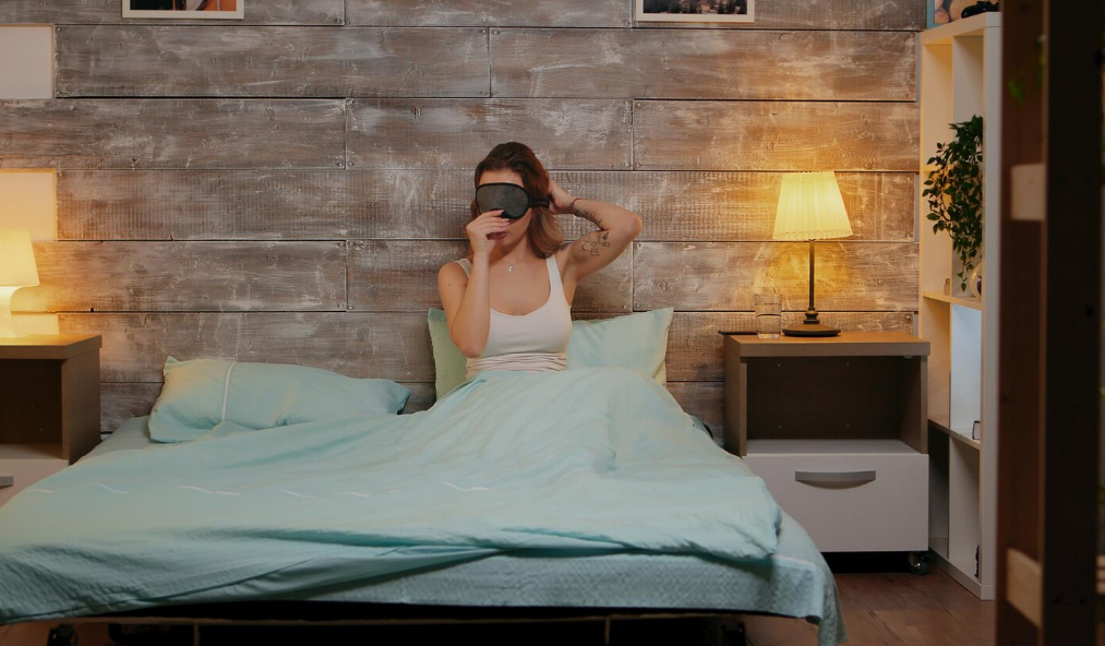 Sleep-friendly bedroom ideas shown through soft lighting, calm bedding, and a sleep mask.